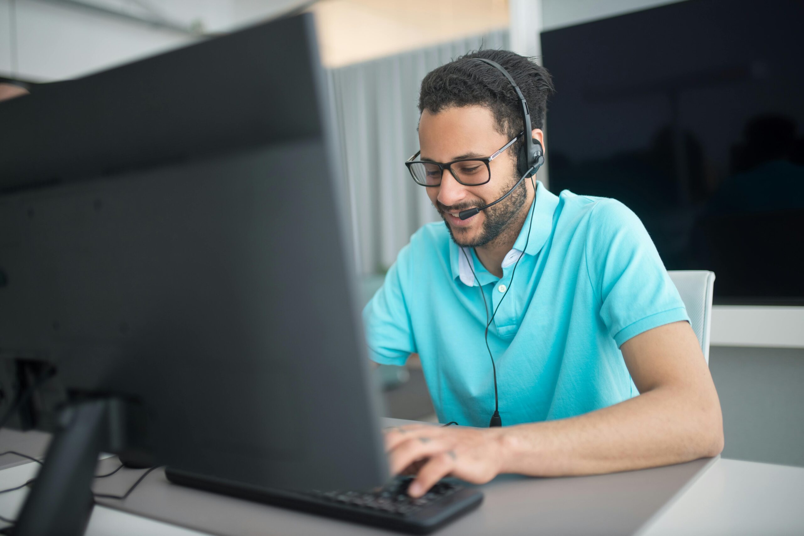 Call center agent working at a computer in an office environment with a headset.